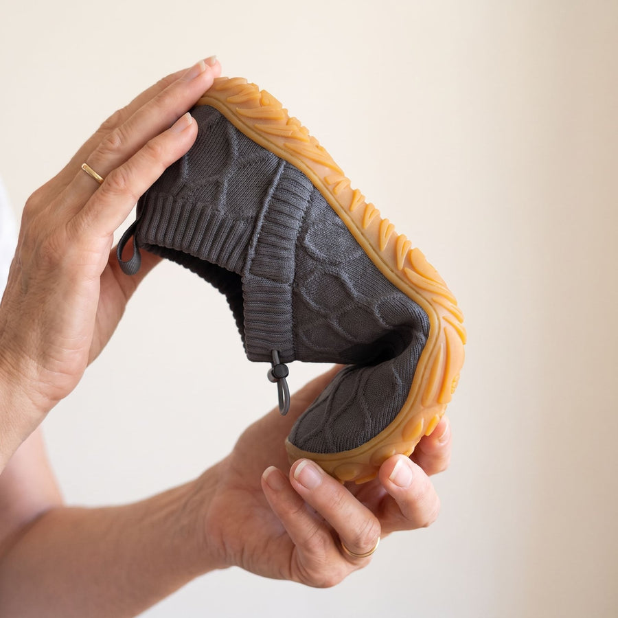Grey StrideFlex shoe bent in half by hand to show the flexible sole